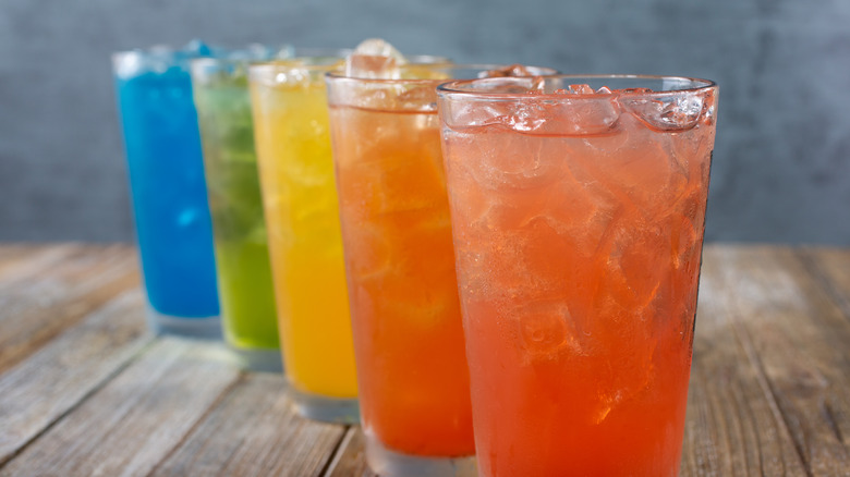 Row of colored artificially flavored drinks with ice