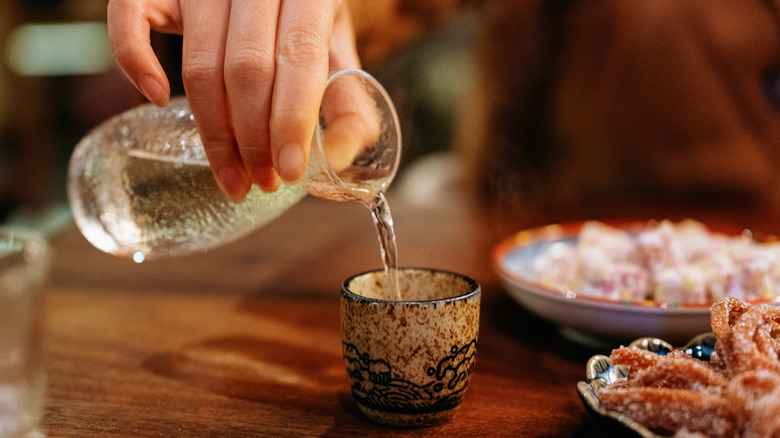 sake being poured into glass at table