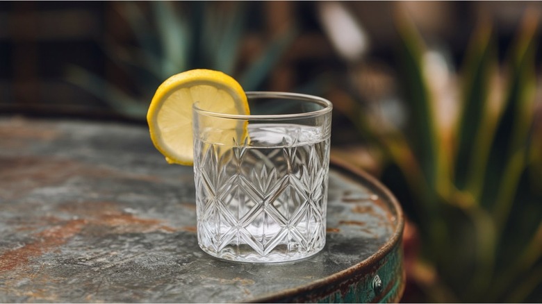 glass of blanco tequila on table with lemon wheel