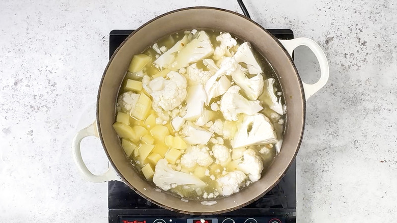 Cauliflower, potato, and stock in pan