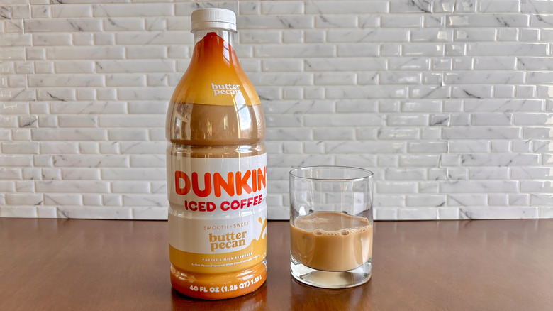 Dunkin' butter pecan iced coffee bottle next to coffee in glass