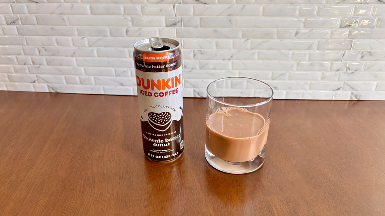 Dunkin' canned iced coffee next to glass with coffee