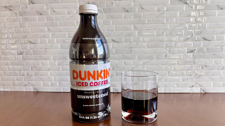 Dunkin' unsweetened bottled iced coffee next to coffee in glass