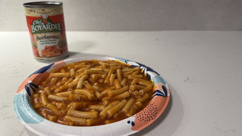 Paper plate on a white counter with Beefaroni and an empty can.