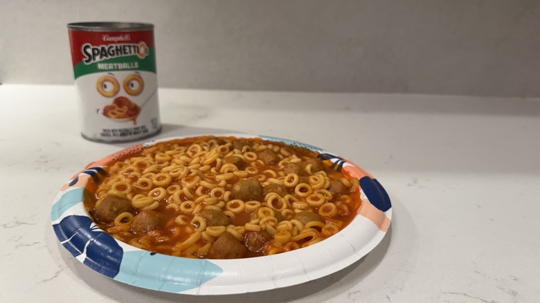 Paper plate on white counter with Spaghettios and an empty can.