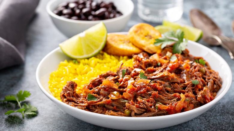 Ropa vieja with rice and plantains in a white dish