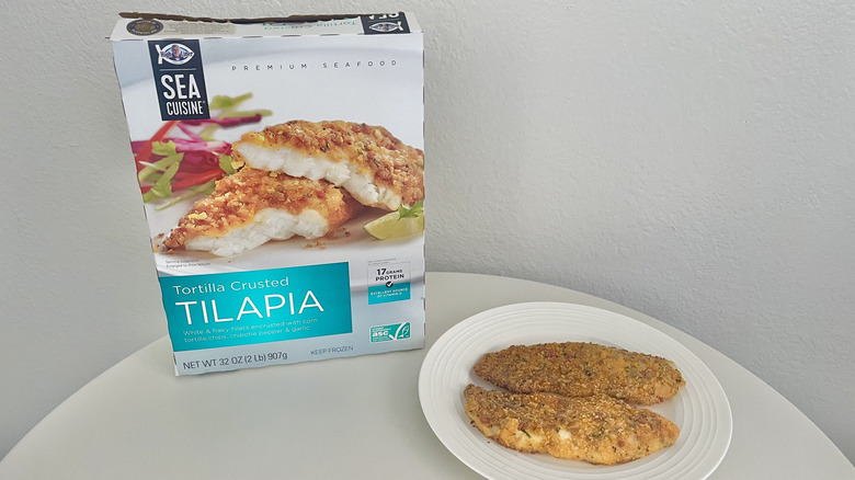 Sea Cuisine tortilla crusted tilapia filets on a plate with the product's packaging behind it.