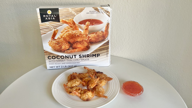 Royal Asia coconut shrimp with Thai sauce are on a plate with the product's packaging behind it.