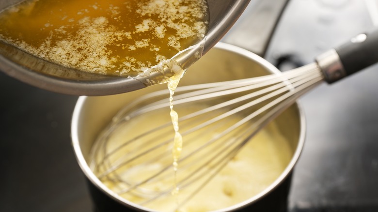 whisking butter into pot of hollandaise