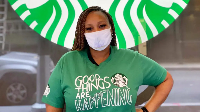 Starbucks employee in front of store sign