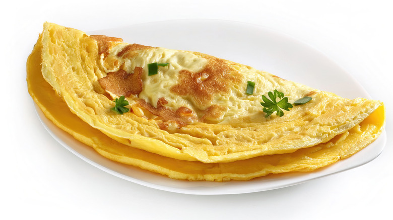 Fried omelet with herbs on a white plate.