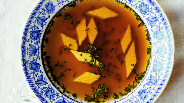 Orange rhombus shapes floating in brown liquid bowl.