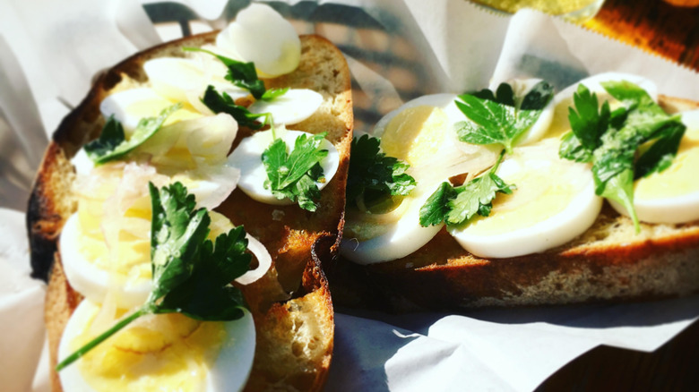 Thick cut toast with hardboiled eggs and fresh parsley on top