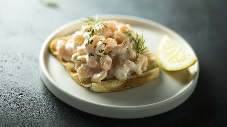 Shrimp on toast with a lemon wedge.