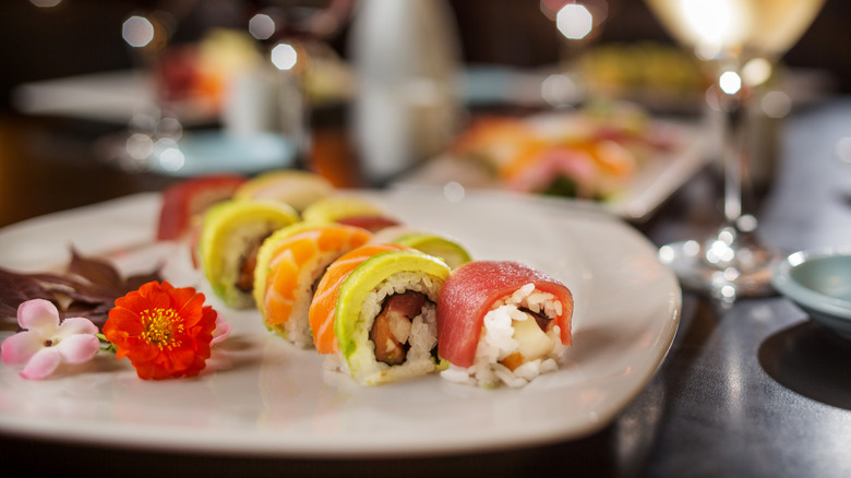 Plate of multicolored sushi rolls on a restaurant plate with edible flowers