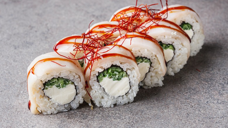 Sushi rolls containing escolar against grey background