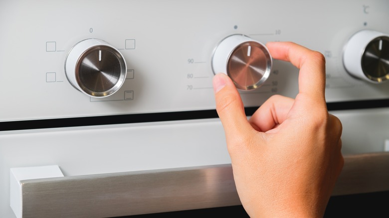 Turning temperature dial on oven