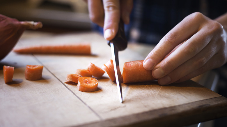 hands chopping carrots