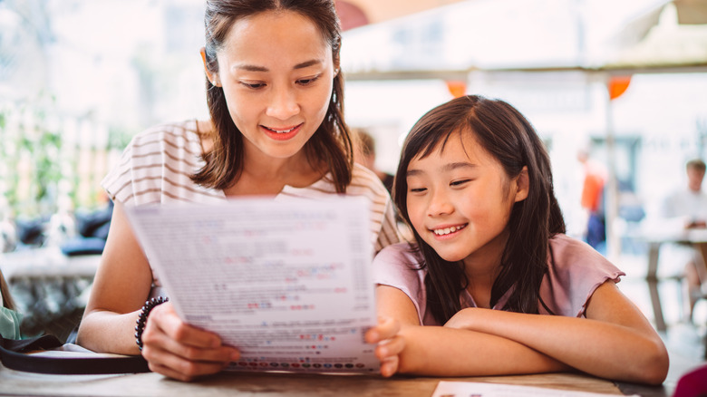 Pair of diners study restaurant menu outdoors