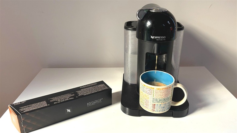 Box of rich chocolate Nespresso pods next to Nespresso machine brewing coffee