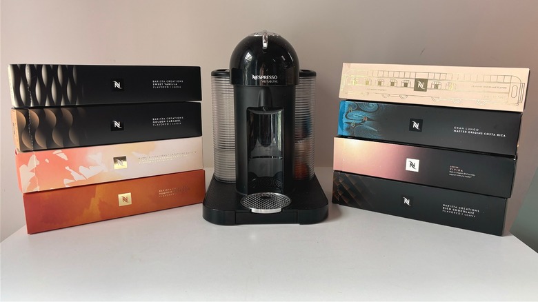 Nespresso machine in between eight boxes of flavored capsules