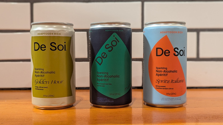 three cans of aperitif drinks with colorful, geometric labels