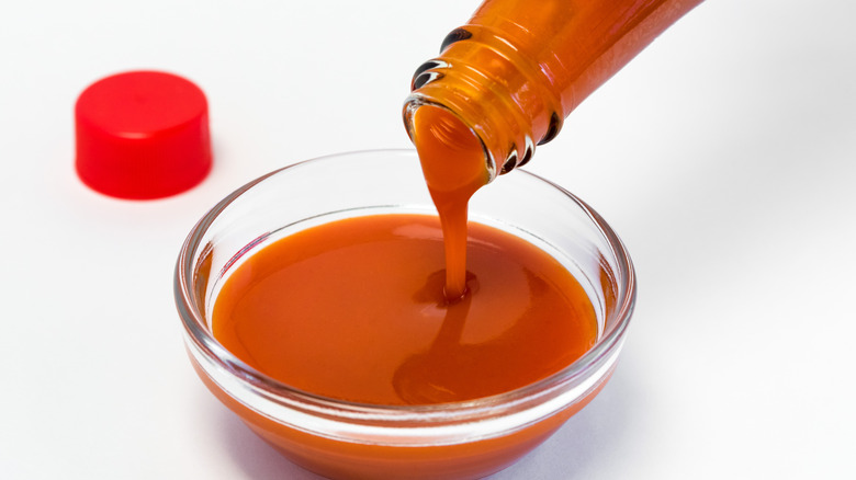 pouring hot sauce into bowl