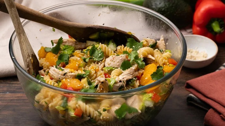 Mandarin chicken salad in a glass bowl with wooden spoons