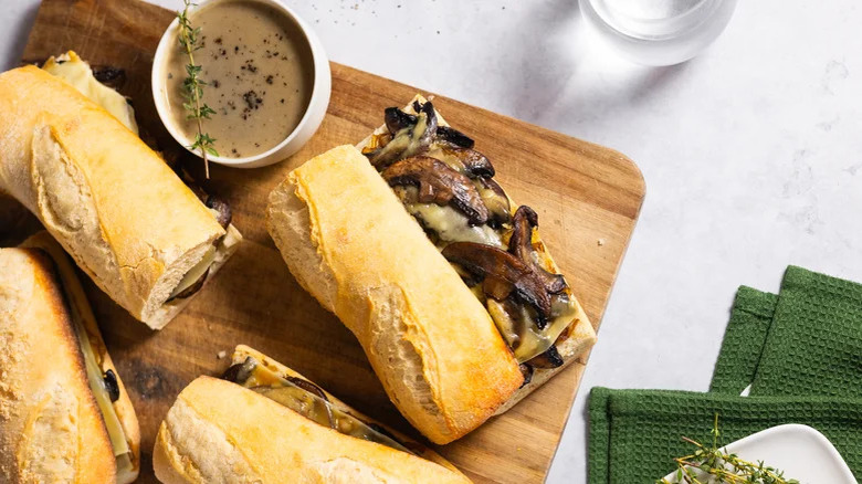 Mushroom French dip sandwiches on cutting board