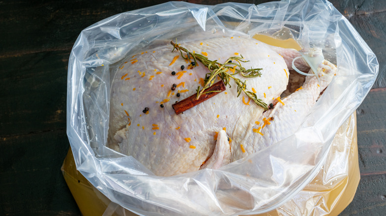 raw turkey brining in bag with herbs and spices