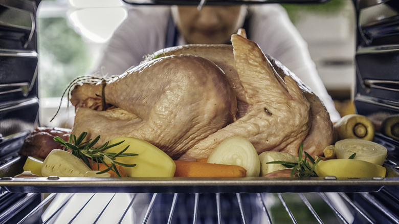 Raw turkey in oven with assorted vegetables