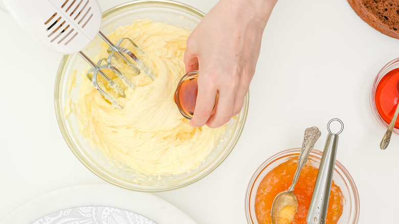 hand adding extract to buttercream