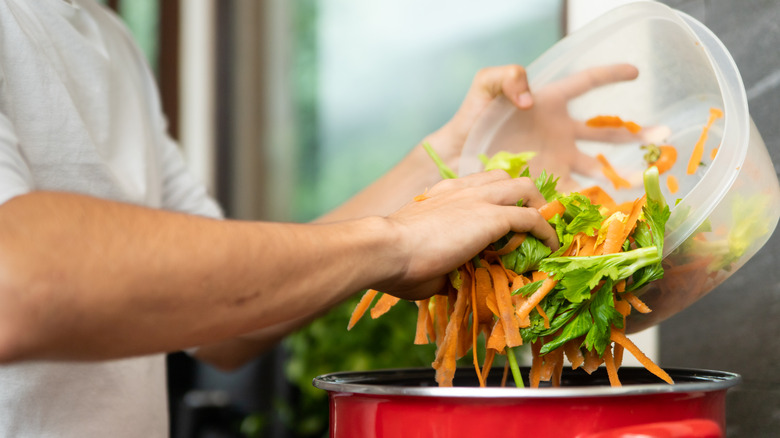 Person pouring vegetable scraps in pot