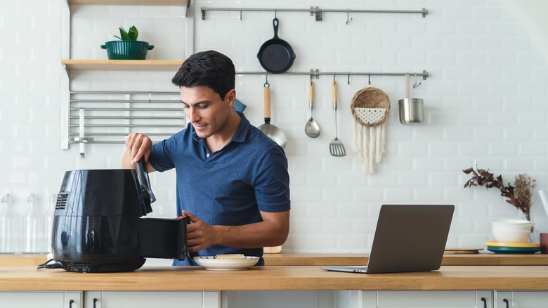 man using tongs in air fryer