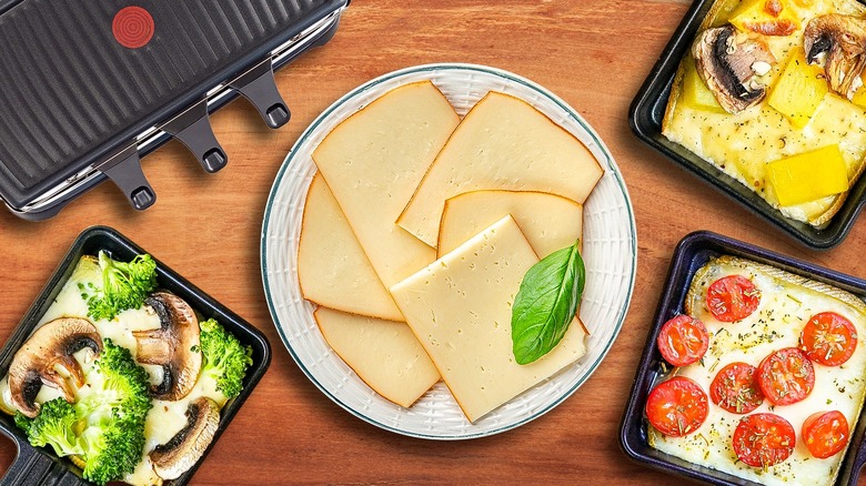 top view of the raclette grill and three various raclette dishes with raclette cheese slices in the middle