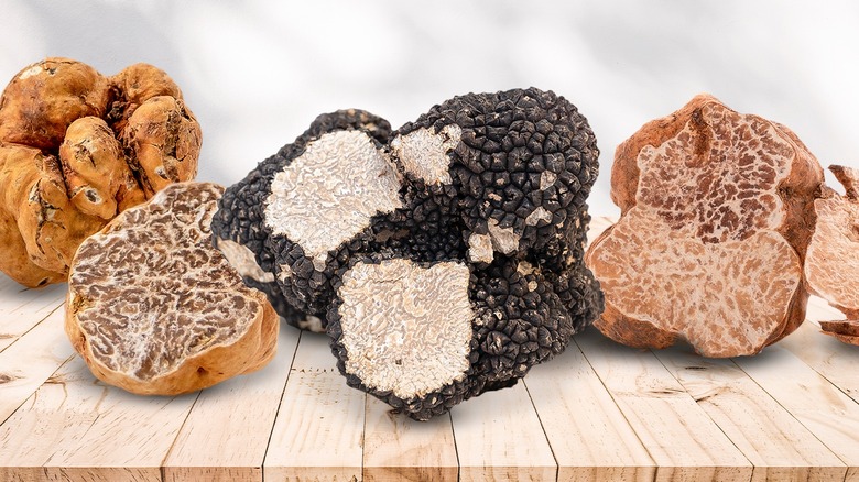 Various truffles lined on a board with several of them sliced to show marbled interior