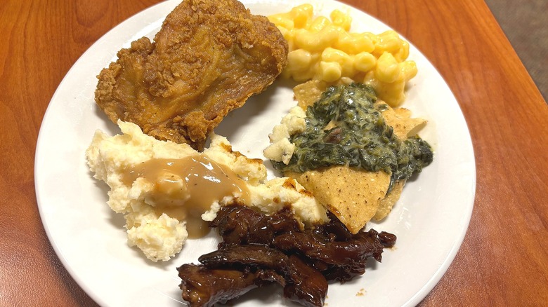 White plate of Golden Corral buffet food on wooden table