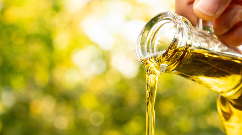 Person pouring out a jug of olive oil