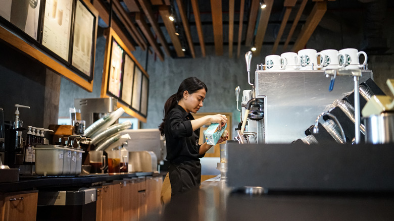 Starbucks barista pouring milk behind the counter