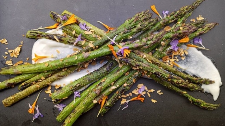 Platter of asparagus, garlic toum, oat crumbs, and edible flowers