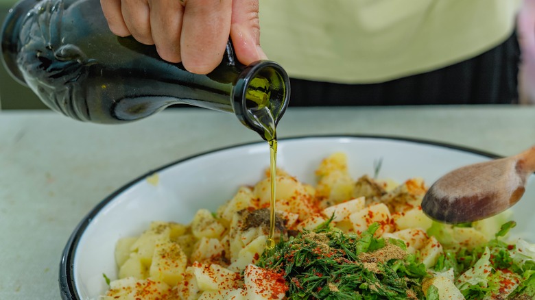 Pouring oil over potato salad