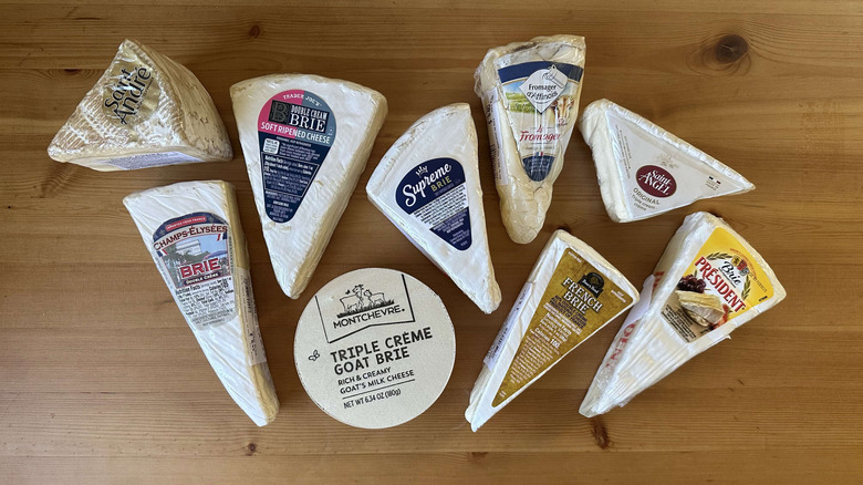 Brie cheeses in plastic packaging sitting on wooden table