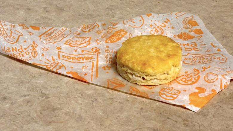 Popeyes biscuit on wrapper on neutral counter top