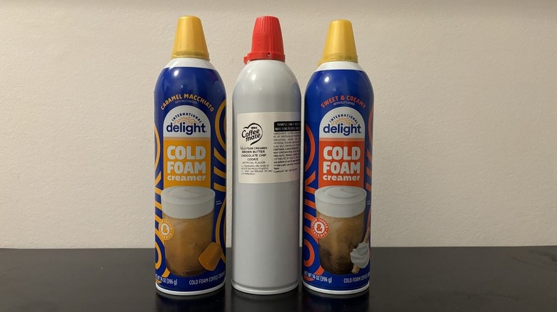 three cans of cold foam on black table