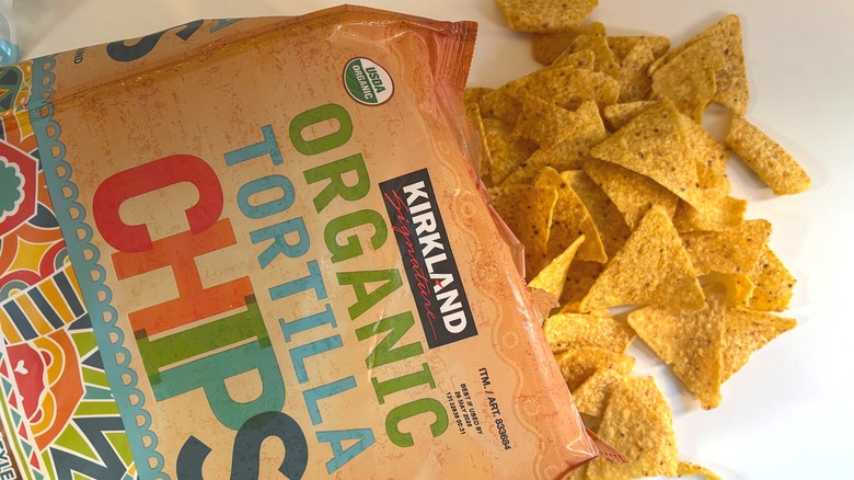 Chips spilling out of bag of Kirkland organic tortilla chips on white table