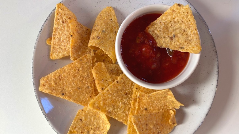 White plate of Kirkland organic tortilla chips and small white bowl of salsa