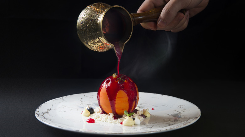 Pouring sauce over red dessert ball