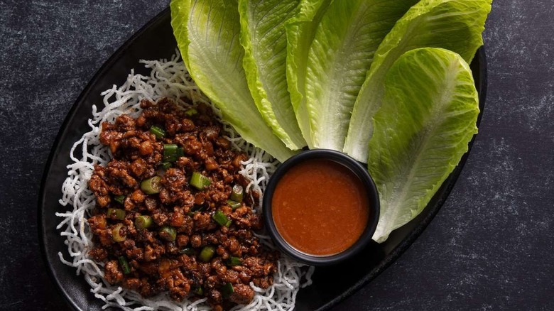 Lettuce, chicken, and dipping sauce on black plate at P.F. Chang's