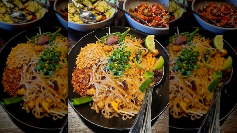 Pad Thai in black bowl surrounded by other dishes at P.F. Chang's