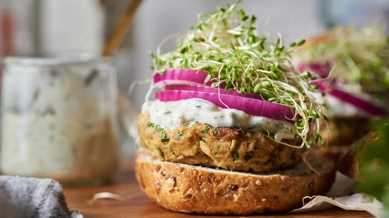 Tuna burger on bun with onion and sprouts